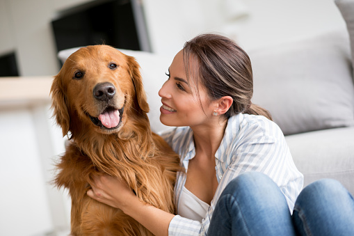 Portrait of an affectionate woman stroking her dog at home and looking very happy - lifestyle concepts