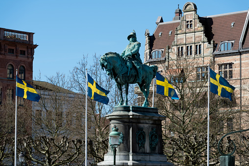 Malmo, Sweden - May 01, 2017: Statue of the king Karl X Gustav on the Stortorget square surrounded with flags of Sweden