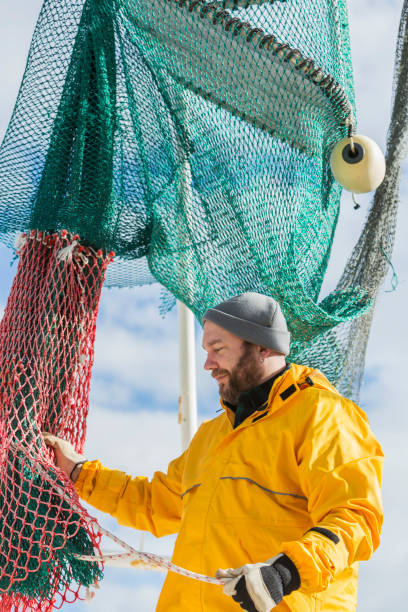 istock Man working on commercial fishing boat, preparing net 823637238