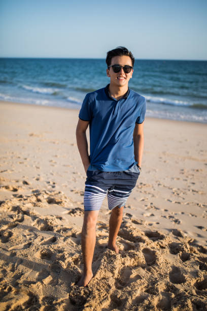 istock Relaxing and smiling asian young man on the beach 823640960