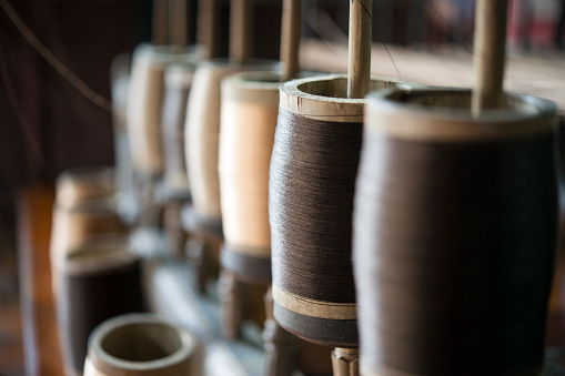 Reels of textile thread at industrial weaving manufacturing machine