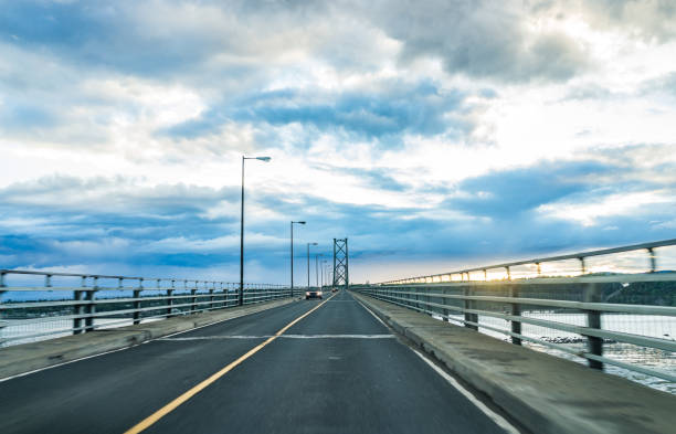 bridge-blick crossing sankt-lorenz-strom von ile d'orleans, quebec, boischatel während des sonnenuntergangs - lawrence quebec canada north america stock-fotos und bilder