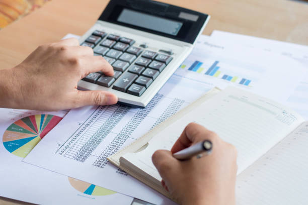 istock woman hand using calculator and writing make note with calculate 823654386