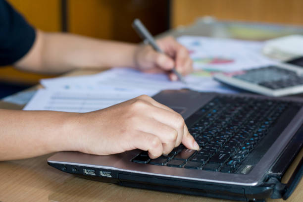 istock woman hand calculate cost and expenses and using laptop for search data result 823660862
