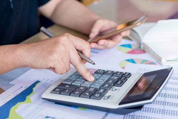 istock close up hand woman calculating about cost and using smartphone searching data in office. 823666178