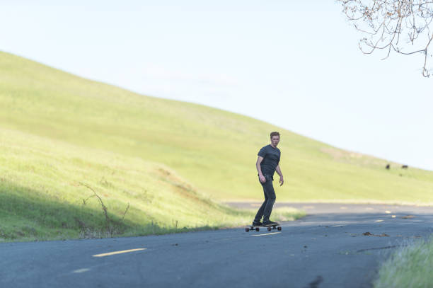 istock Mid adult man longboards down rural highway 823668570
