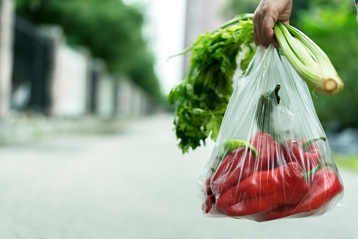 woman taking a bag of vegetables walking on road