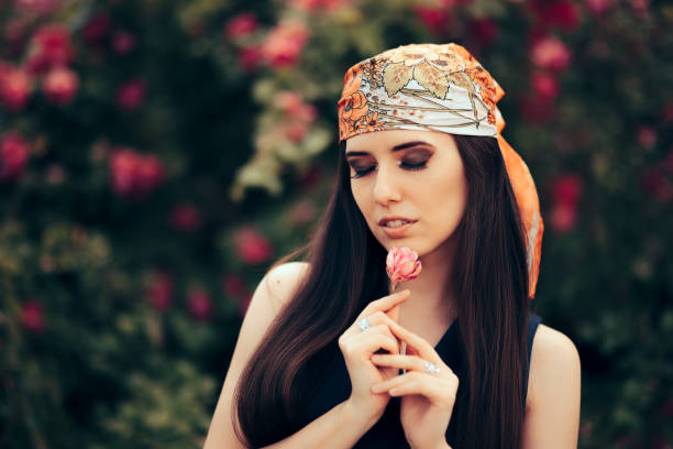 Fashion Woman Wearing Head Scarf in 70’s Retro Style Outfit Beautiful fashionista in stylish vintage look admiring a floral garden bandana photos stock pictures, royalty-free photos & images