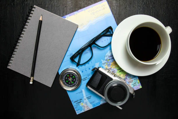 istock Top view of office desk workspace with coffee cup, camera ,world map ,compass,notebook,pencil ,glasses on wooden background 823673030