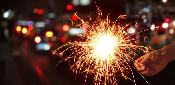 istock Man hand holding sparkler or firework on street night background 823686900
