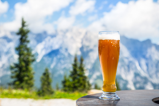 Beer. Cold golden draft beer in glass over alps. Tasty beer and tourist season in the mountains or the Alps.