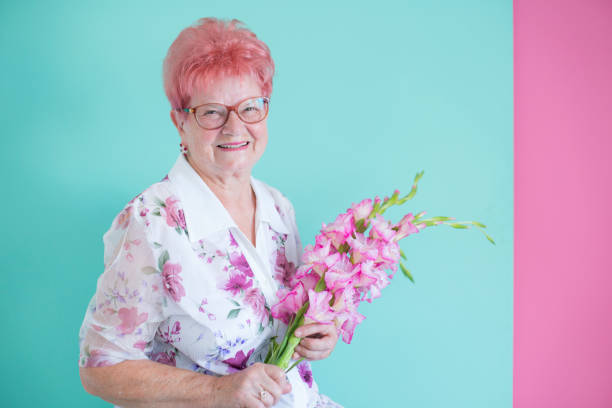 porträt von senior frau mit blumen - gladiolus flower floral pattern single flower stock-fotos und bilder
