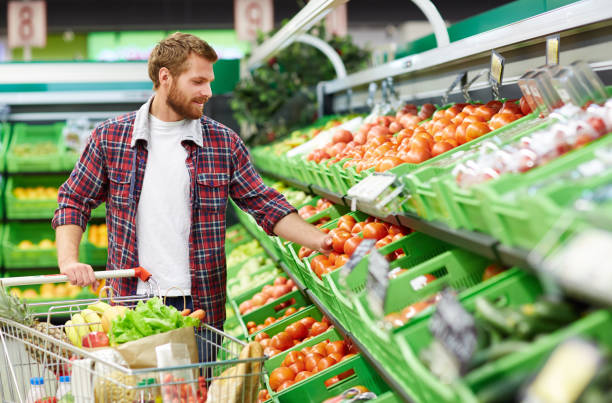 man defining quality of tomato in supermarket - food shopping imagens e fotografias de stock
