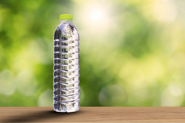 istock Drinking water bottle with soft shadow on wooden tabletop on blurred green bokeh background with soft sunlight, healthy drinking concept 823704514