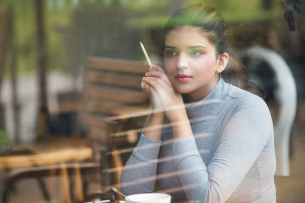 istock Dreamful young student with pencil sitting in cafe 823719122