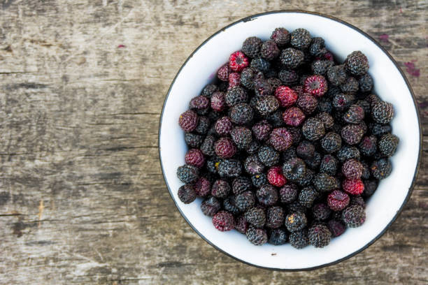 istock Ripe blackberries in rustic bowl on old wooden background. Top view 823719180