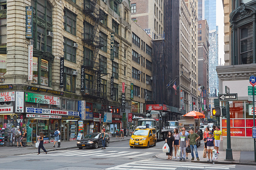 Manhattan, New York, USA - August 16, 2014.\nBusy traffic pulsing through the Times Square in New York City. Road full of cars, yellow cabs and sounds. Crossing the street. Every day life.