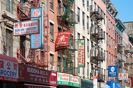 New York - September 7, 2016: Chinatown street with building facades with signs in a sunny day in New York. The district hosts the largest Chinese enclave in the Western Hemisphere.