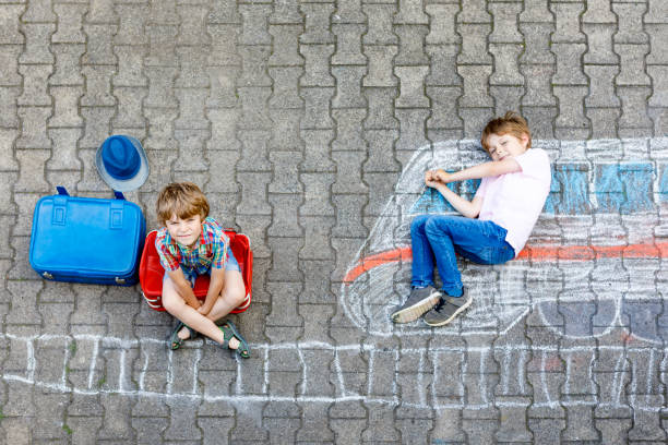 istock Two little kids boys having fun with train picture drawing with colorful chalks on ground 823730352