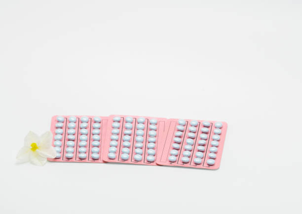 drei blister mit hormontabletten für behandlung der menopause frauen und blumen auf weißem hintergrund - contraceptive pill birth control pill sex education stock-fotos und bilder