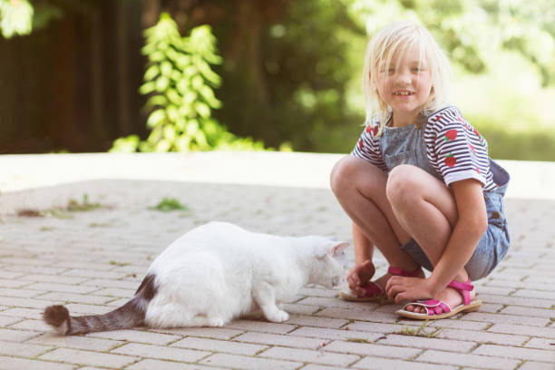 istock Blond girl with white cat in backyard 823733864