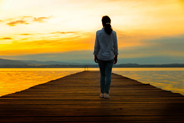 istock Sunrise - woman on wooden jetty 823736700