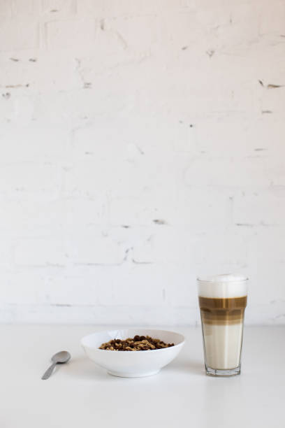 glass of coffee latte and cornflakes in bowl with spoon