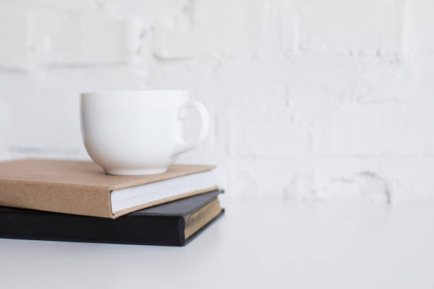 istock white cup of coffee on two books on white tabletop with copy space 823744080