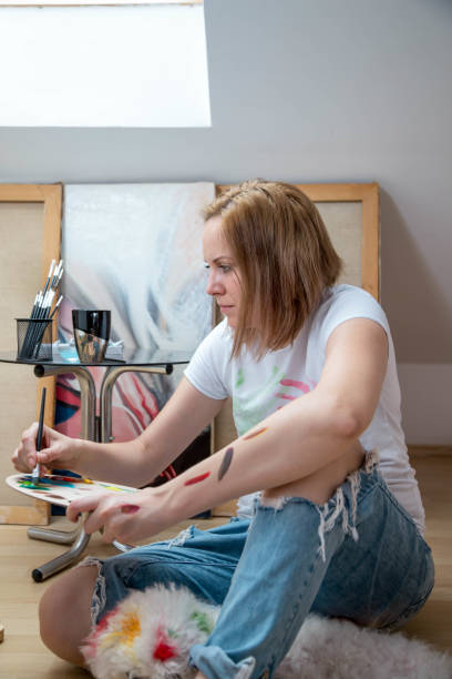 istock Happy young woman paints on canvas 823751162