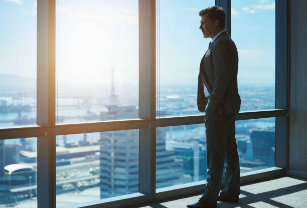 istock Mature business leader looking through large windows at city bel 823759508