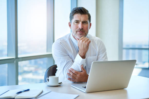 istock Handsome mature businessman with laptop in office looking seriou 823763644