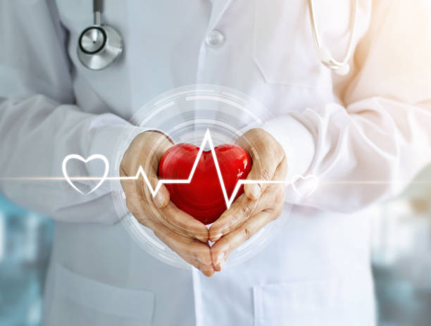 Doctor with stethoscope and red heart shape with icon heartbeat in hands on hospital background Doctor with stethoscope and red heart shape with icon heartbeat in hands on hospital background heart disease photos stock pictures, royalty-free photos & images
