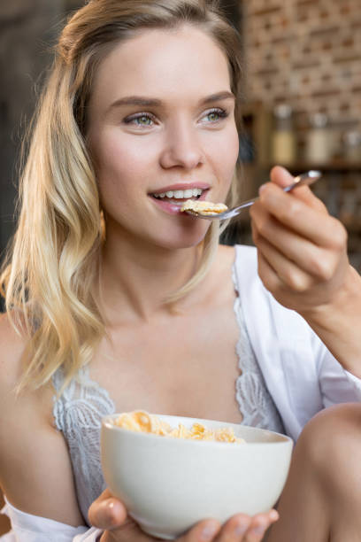 istock Young blonde attractive woman having corn flakes on breakfast in kitchen 823771126