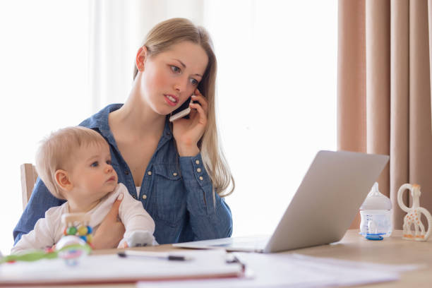 istock Working mother with baby in her lap working from home 823789338