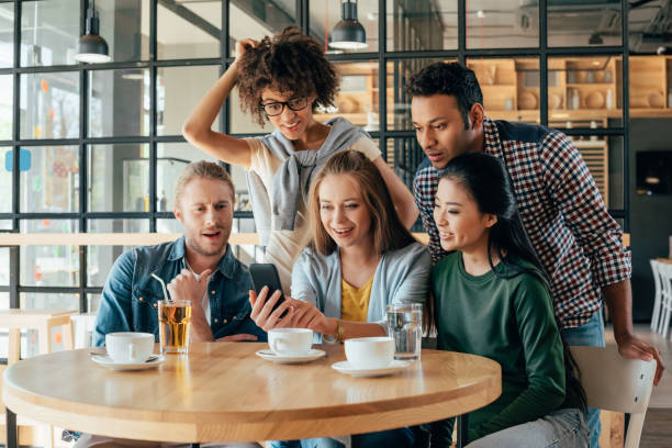 istock Young happy multiethnic friends looking at smartphone while resting in cafe 823797106