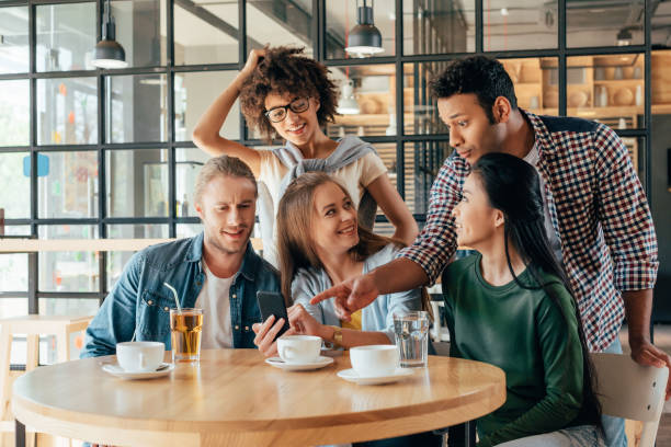 istock Young happy multiethnic friends looking at smartphone while resting in cafe 823799848