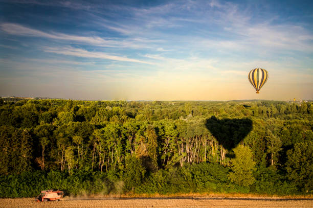 Vertical shot of hot air balloon casting a shadow over rural fields