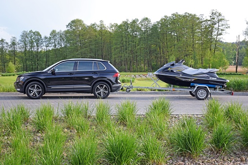 Olsztyn, Poland - May 12th, 2016: Volkswagen Tiguan with trailer and jet ski parked on the road. This model is one of the most popular sport utility vehicles in Europe.