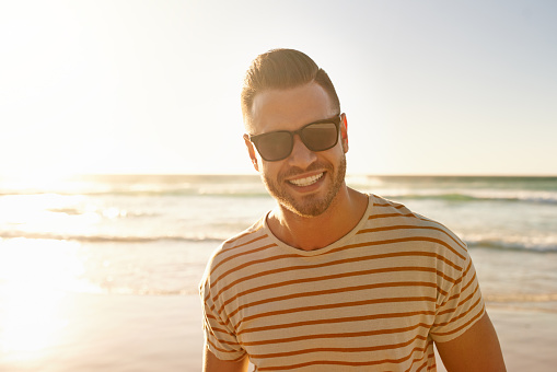 Cropped portrait of a handsome young man standing on the beach at sunset