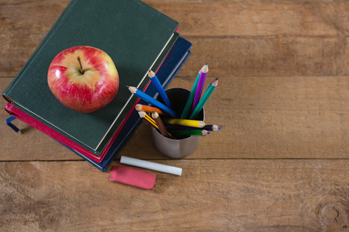 Close-up of school supplies and books stack with apple on top