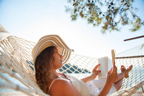 istock Woman in a hammock with book on holiday 823825982