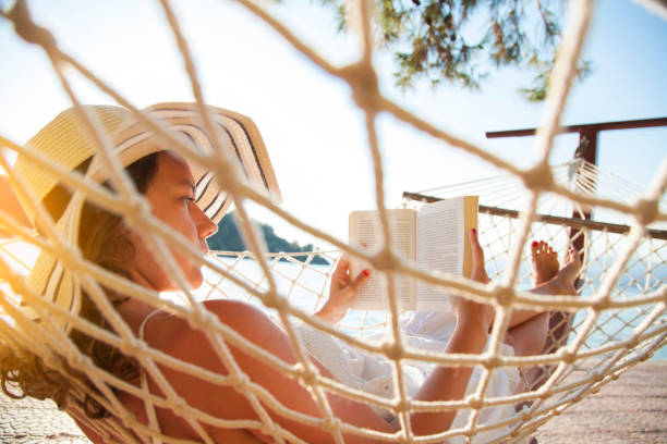 istock Woman in a hammock with book on holiday 823826010