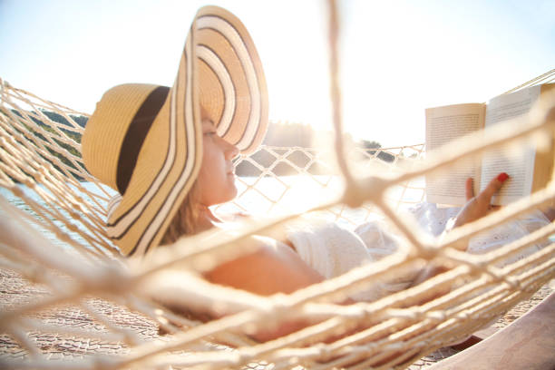 istock Woman in a hammock with book on holiday 823826070
