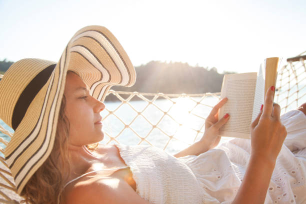 istock Woman in a hammock with book on holiday 823826082