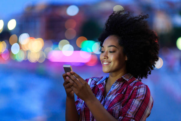 istock Smiling woman using smart phone at night on street 823830048