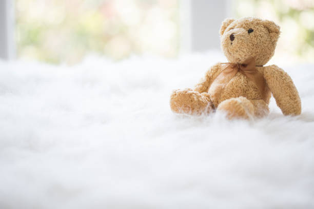 Teddy bear with a bow Teddy bear with a bow, on white fluffy blanket, by the window. fluffy blanket stock pictures, royalty-free photos & images
