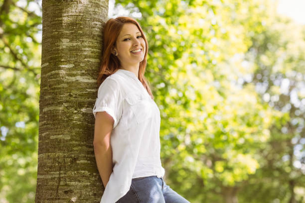 istock Portrait of a pretty redhead leaning against trunk 823845016