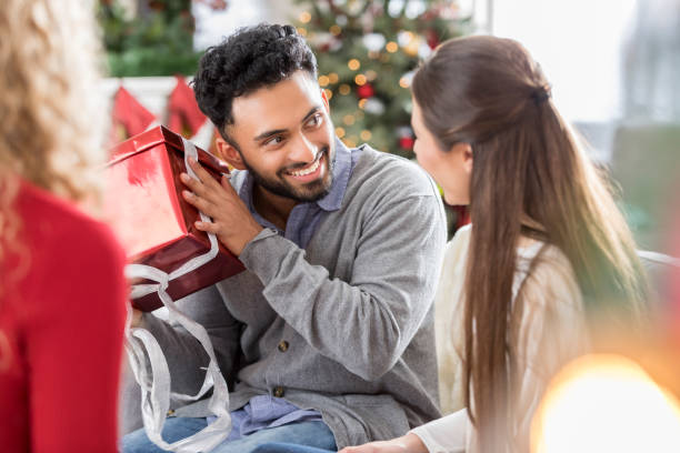 istock Man shakes Christmas present during celebration with friends 823846084