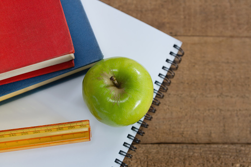 Close-up of green apple and school supplies on wooden table