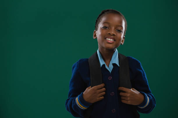 School girl with backpack standing against chalk board stock photo